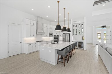 Kitchen with light wood-style flooring, a spacious island, a kitchen breakfast bar, white cabinets, and recessed lighting