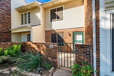 View of exterior entry featuring brick siding and a gate