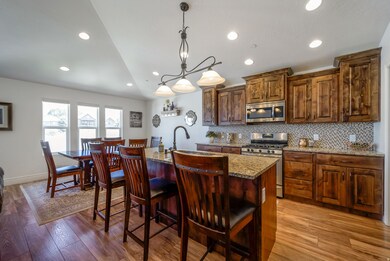 Kitchen featuring light stone countertops, recessed lighting, a kitchen island with sink, hanging light fixtures, and stainless steel appliances