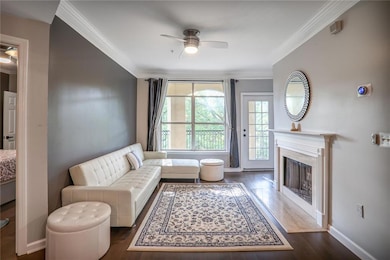 Living area with ceiling fan, dark wood-style flooring, crown molding, and a premium fireplace