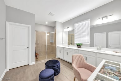 Bathroom with a shower stall, double vanity, and light wood-type flooring