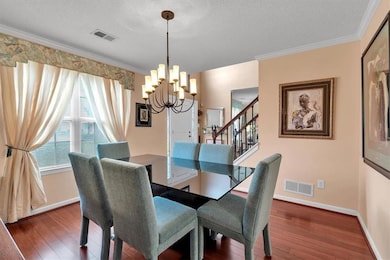 Dining space featuring hardwood / wood-style floors, a chandelier, a textured ceiling, baseboards, and ornamental molding