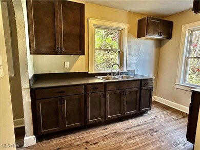 Kitchen with dark brown cabinetry, light wood-style flooring, dark countertops, and arched walkways
