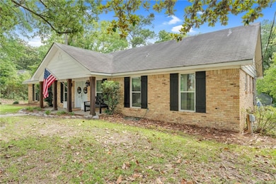 Single story home featuring brick siding, a porch, and a shingled roof