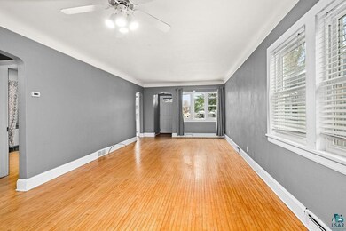 Unfurnished living room featuring baseboards, arch
