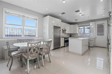 Kitchen with appliances with stainless steel finishes, a kitchen island, white cabinetry, recessed lighting, and light countertops