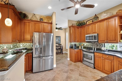 Kitchen featuring backsplash, open shelves, appliances with stainless steel finishes, a ceiling fan, and brown cabinets