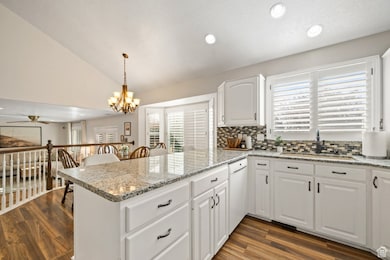 Kitchen featuring white cabinetry, light stone counters, recessed lighting, tasteful backsplash, and plenty of natural light