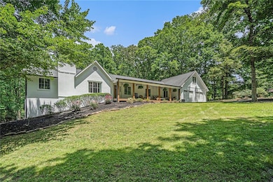View of front of home featuring a front yard, covered porch, and an attached garage
