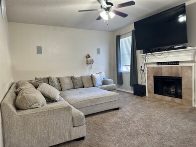 Living room with carpet floors, a textured ceiling, a fireplace, and ceiling fan