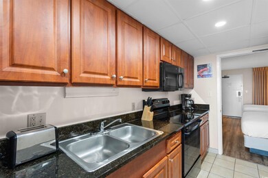 Kitchen with brown cabinets, light tile patterned flooring, a sink, a drop ceiling, and black appliances