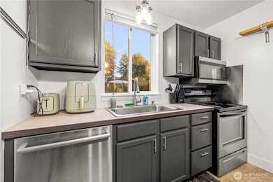 The kitchen is equipped with sleek stainless steel appliances and a dedicated workspace. A window over the sink lets in natural light and provides a pleasant view while you wash dishes.