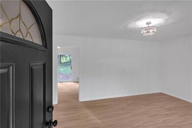 Foyer featuring light wood-style flooring, baseboards, and a chandelier