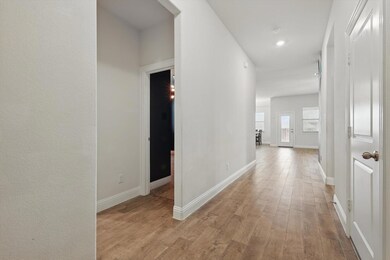 Corridor with light wood-type flooring and baseboa