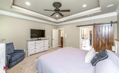 Carpeted bedroom with ornamental molding, a barn d