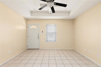 Entryway with light tile patterned flooring, ceiling fan, and a tray ceiling