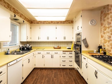 The kitchen, with its cheerful yellow countertops, vintage cabinetry, and whimsical wallpaper, feels like a place where generations have gathered over hearty meals and everyday stories.