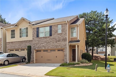 View of front facade featuring concrete driveway, brick siding, a front yard, and an attached garage