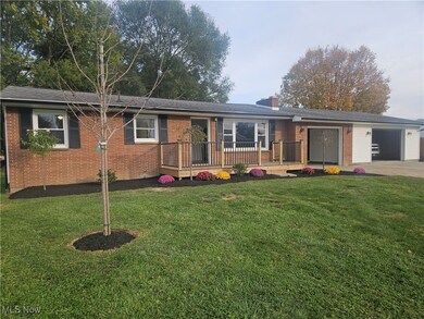 Single story home featuring a wooden deck, brick siding, a front yard, and a chimney