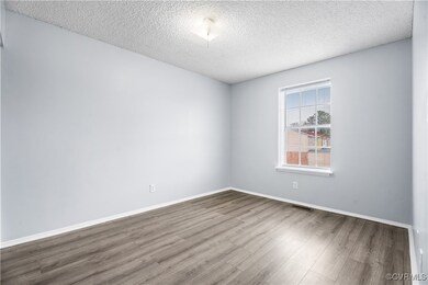Empty room with a textured ceiling and hardwood / wood-style flooring