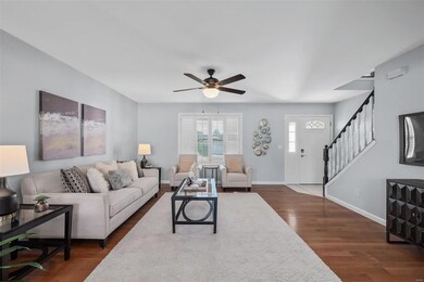 Living room has wood flooring, ceiling fan with li