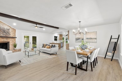 Dining space featuring light wood-type flooring, a chandelier, a ceiling fan, a fireplace, and french doors