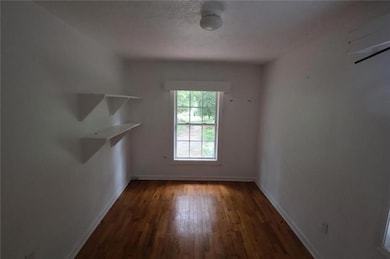 Unfurnished room with baseboards and dark wood-type flooring