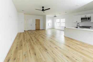 Unfurnished living room featuring sink, ceiling fa