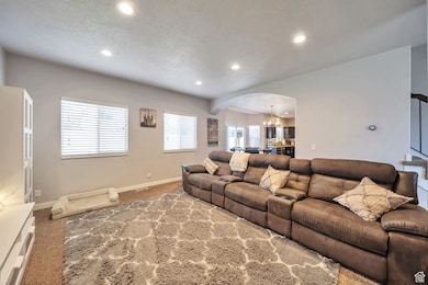 Living room featuring arched walkways, a chandelier, carpet floors, recessed lighting, and a textured ceiling