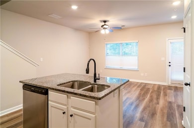 Kitchen featuring stainless steel dishwasher, light wood-type flooring, white cabinets, recessed lighting, and a kitchen island with sink