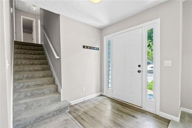 Foyer entrance with stairs, baseboards, and wood finished floors