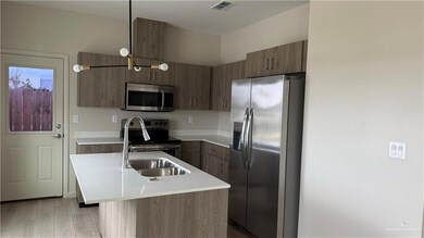 Kitchen with sink, hanging light fixtures, light wood-type flooring, an island with sink, and stainless steel appliances