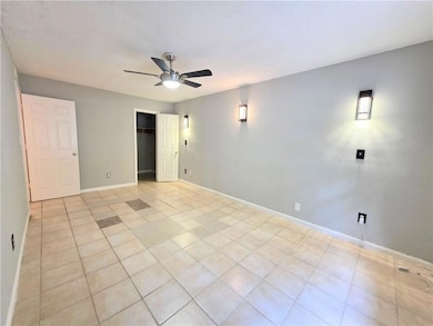 Unfurnished room featuring ceiling fan, baseboards, and light tile patterned flooring