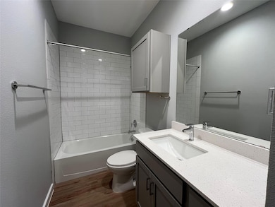 Full bathroom with dark wood-style flooring, shower / washtub combination, vanity, and a textured wall
