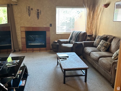 Living area with a textured wall, a fireplace, and carpet