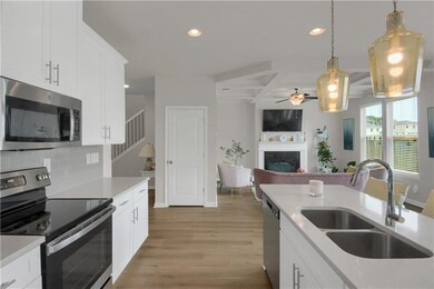 Kitchen with stainless steel appliances, a fireplace, recessed lighting, a ceiling fan, and tasteful backsplash