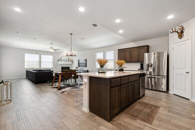 Kitchen featuring plenty of natural light, a center island with sink, ceiling fan with notable chandelier, and appliances with stainless steel finishes