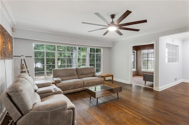 Living room with ornamental molding, dark wood-style floors, and ceiling fan