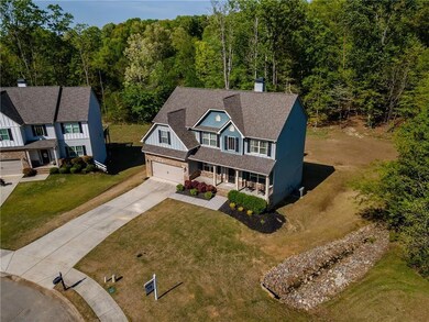 View of front of house featuring covered porch, driveway, roof with shingles, a chimney, and a garage
