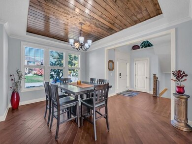 Dining space with a raised ceiling, crown molding, dark hardwood / wood-style flooring, and a notable chandelier