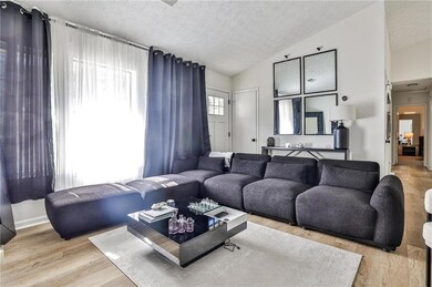 Living area with vaulted ceiling, wood finished floors, and a textured ceiling