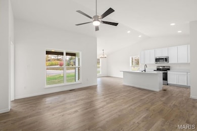 Unfurnished living room with a chandelier, light wood-type flooring, a ceiling fan, recessed lighting, and high vaulted ceiling