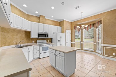Kitchen featuring ornamental molding, a center island, decorative light fixtures, white cabinetry, and white appliances