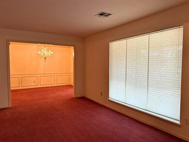 Empty room with a chandelier and carpet flooring