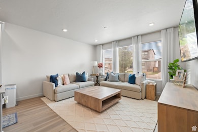 Living area featuring healthy amount of natural light, light wood-type flooring, a textured ceiling, and recessed lighting
