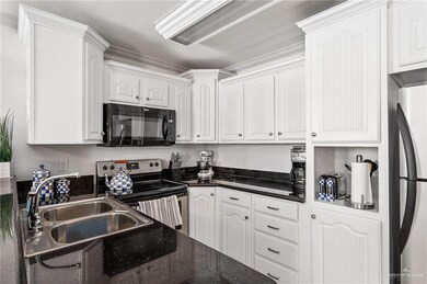 Kitchen featuring appliances with stainless steel finishes, white cabinetry, sink, and dark stone counters
