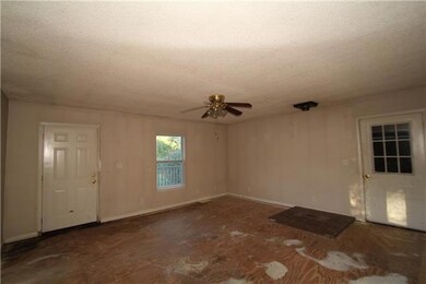 Living room open to dining and kitchen areas with rear deck access.