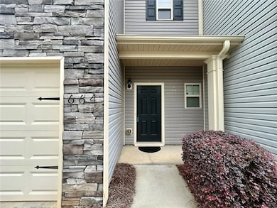 Doorway to property with stone siding, covered porch, and an attached garage