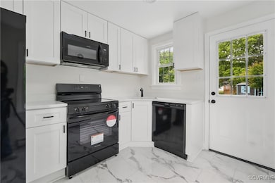 Kitchen with black appliances, light marble finish