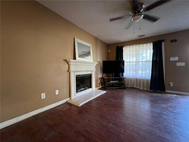 Unfurnished living room with a ceiling fan, a fireplace with raised hearth, wood finished floors, and a textured ceiling